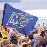 Merrimack College marching band with large MC flag