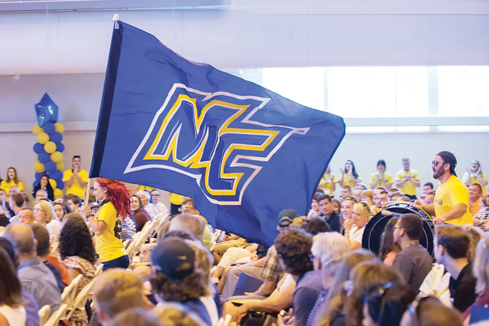 Merrimack College marching band with large MC flag